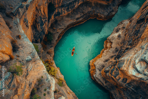 A lone canoe floats in the turquoise waters of a majestic canyon, surrounded by rugged cliffs, highlighting the vastness of nature.