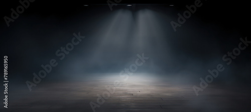 A dark foggy room with a spotlight shining down, empty floor.