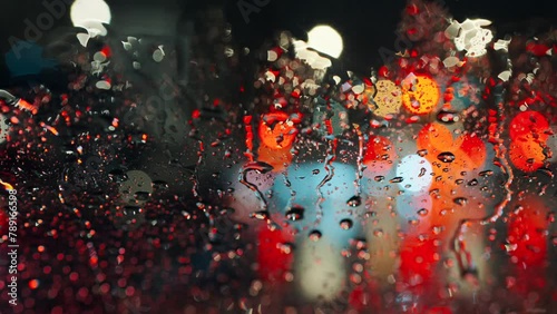 Lights of the evening city and passing cars through a wet rainy window.