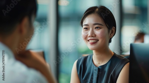 Una donna giapponese sorridente è impegnata in una conversazione con un collega in ufficio photo