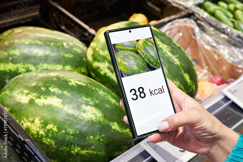 Checking calories on watermelon in store with smartphone