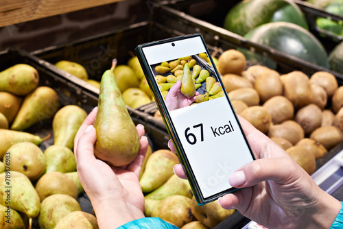 Checking calories on pear fruit in store with smartphone © Sergey Ryzhov