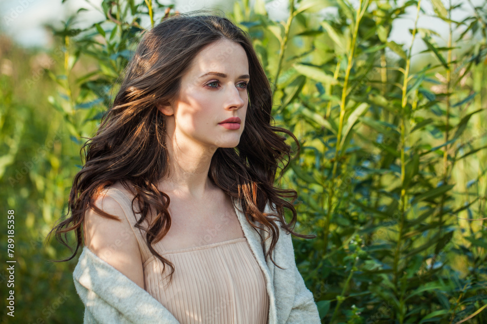 Charming healthy young brunette woman with fresh clear skin and long dark brown hair outdoors on green grass background, air portrait Charming healthy young brunette woman with fresh clear skin and long dark brown hair outdoors on green grass background, air portrait