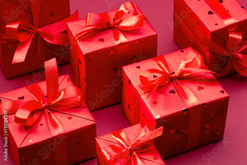 Set of stylish boxes with gifts in red paper with hearts, decorated with red satin ribbon with bows. Copy space.