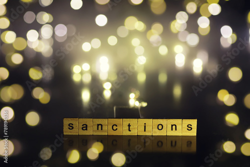 word sanctions spelled in letters on table made of wooden block letters with dramatic lighting and smoke