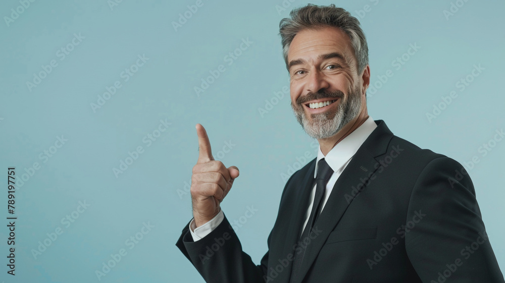 Middle-aged businessman pointing finger isolated on light blue background with copy space Middle-aged businessman pointing finger isolated on light blue background with copy space