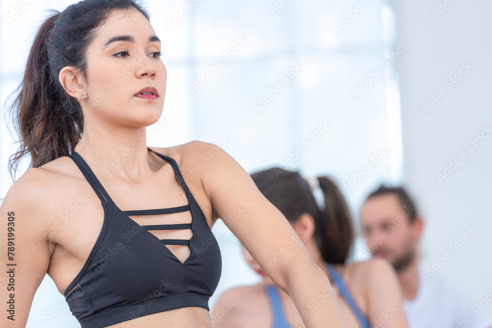 A woman in athletic wear maintains a focused gaze while performing a yoga pose, embodying control and serenity. A woman in athletic wear maintains a focused gaze while performing a yoga pose, embodying control and serenity.