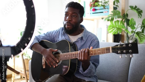 smiling african american teacher giving class and recording online guitar tutorial