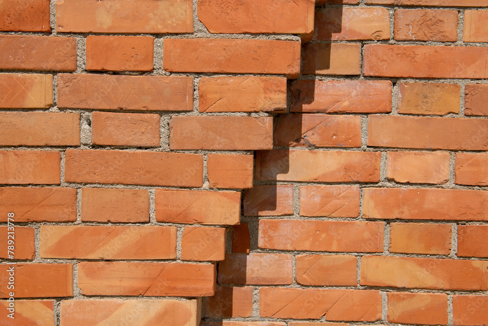 Fototapeta premium exposed brick wall, construction detail of a wall with decorative elements given by the simple exchange of textures, joint between exposed bricks on the facade of a prestigious building.