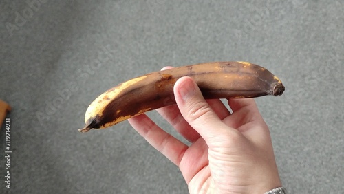 Slika na platnu Man holds a very overripe banana in his hand