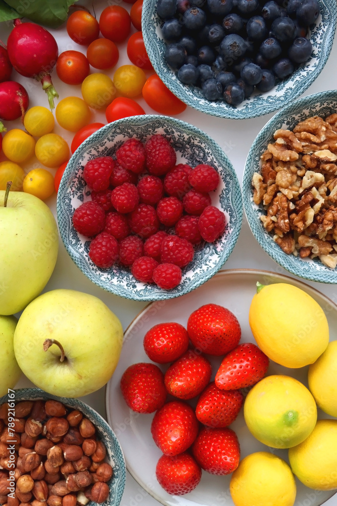 Apples, lemons, bananas, berries, carrots, leek, tomatoes, radishes, spinach and various nuts on white background. Healthy seasonal fruit and vegetable. Top view. Apples, lemons, bananas, berries, carrots, leek, tomatoes, radishes, spinach and various nuts on white background. Healthy seasonal fruit and vegetable. Top view.