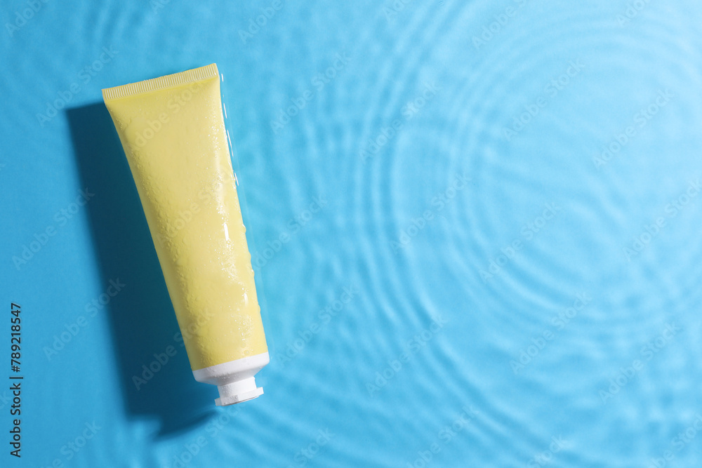 Tube with moisturizing cream in water on light blue background, top view. Space for text Tube with moisturizing cream in water on light blue background, top view. Space for text