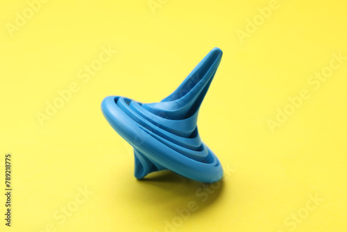 One blue spinning top on yellow background, closeup