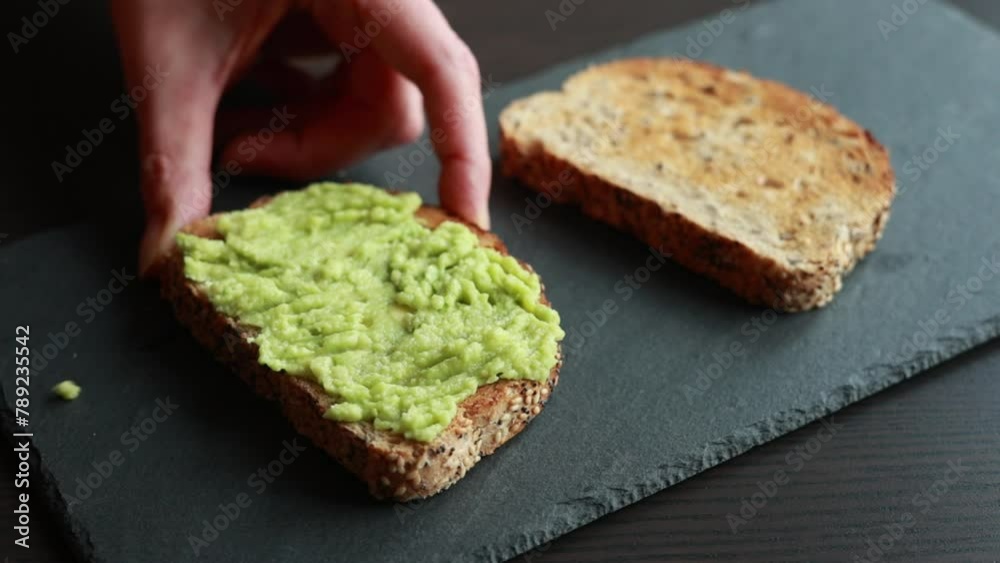 A captivating close-up video of someone spreading creamy avocado onto a slice of toast bread, highlighting the simplicity and deliciousness of this nutritious snack A captivating close-up video of someone spreading creamy avocado onto a slice of toast bread, highlighting the simplicity and deliciousness of this nutritious snack