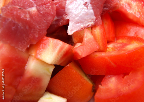 raw meat with tomatoes. chopped tomato with pieces of meat. preparing meal with tomatoes and meat. food details.