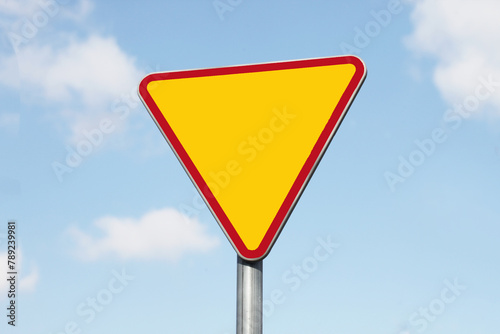 Give way road sign. Traffic safety. Empty copy space isolated on blue sky. Priority lane ahead.