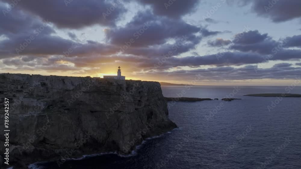 Cliff coastal landscape sun shining below Menorca coastal lighthouse aerial drone panning slow motion