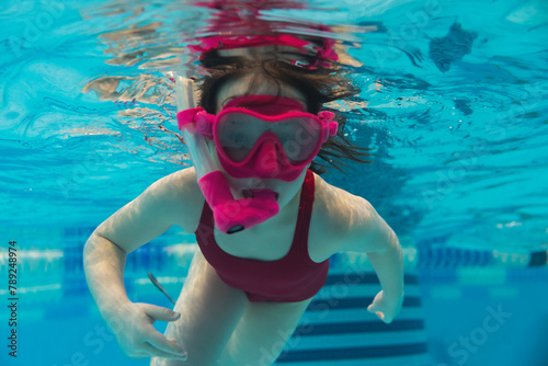 6 year old girl child is engaged in scuba diving with a snorkel and mask in the pool.