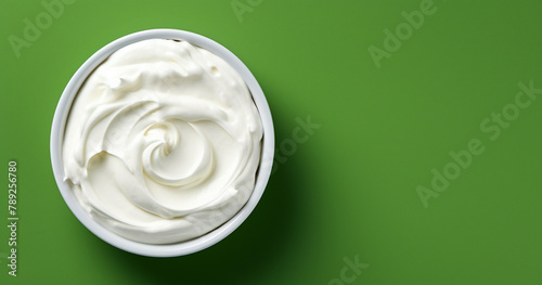 Top view of bowl with white quark or cream on side of green background with copy space сreated with Generative Ai