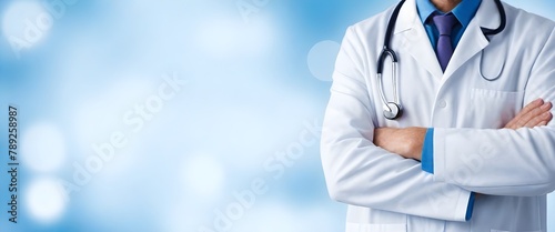 Caucasian adult in a white lab coat with a stethoscope around the neck, arms crossed, standing in front of a blurred blue background