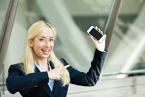 Happy businesswoman pointing with finger at mobile phone