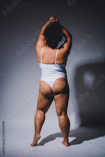 rear view of empowered afrolatina young woman in lingerie posing on white background