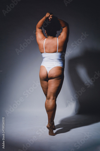 rear view of empowered afrolatina young woman in lingerie posing on white background photo