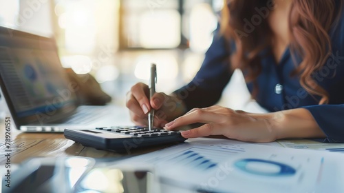 Woman accountant use calculator and computer with holding pen on photo