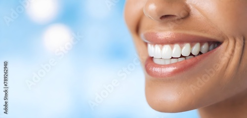Person s close-up smile showing white teeth  with a blurred light blue background