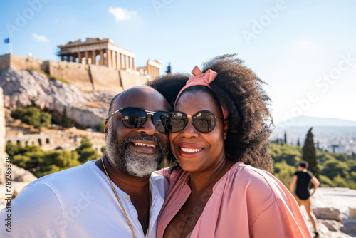 An affectionate couple takes a selfie with the Acropolis in the background, capturing travel and adventure in Athens