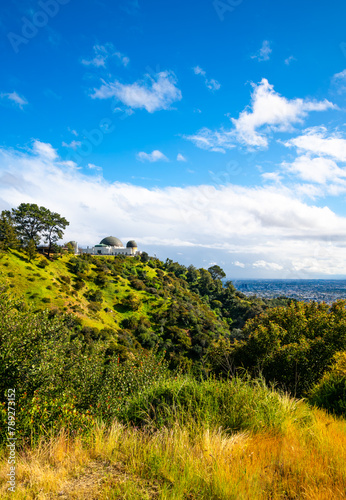 Historic observatory in Los Angeles, California. Monument, museum and popular attraction high above downtown with panoramic view on a sunny spring day. Lush vegetation of Griffith park and blue sky.