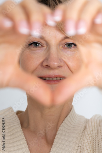 Portrait of happy woman. Female hands making sign Heart by fingers. Looking at camera. High quality photo