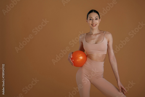 With red ball. Beautiful fitness woman is in the studio