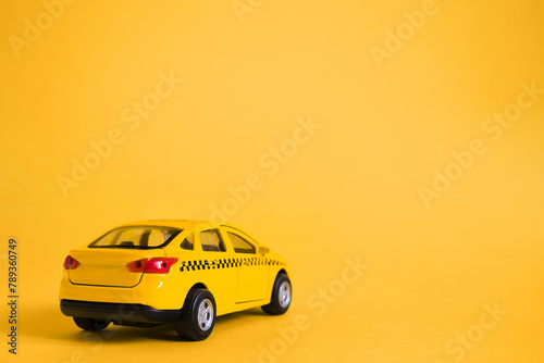 Urban taxi and delivery service concept. Toy yellow taxi car model. Copy space for text  banner. Online mobile application order taxi service.