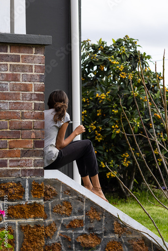 young girl turned away from camera sitting on steps of old house photo