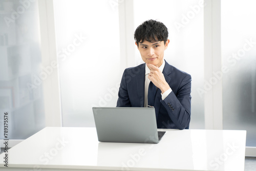 ノートパソコンで資料作成時に悩む男性ビジネスマン