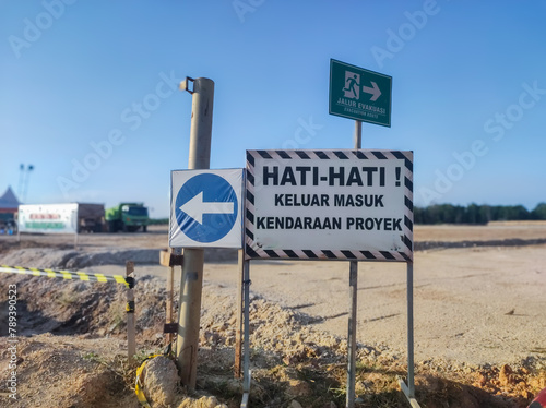 warning board with the words Hati-hati keluar masuk kendaraan proyek dan jalur evakuasi in English Be careful in and out of project vehicles and evacuation routes photo