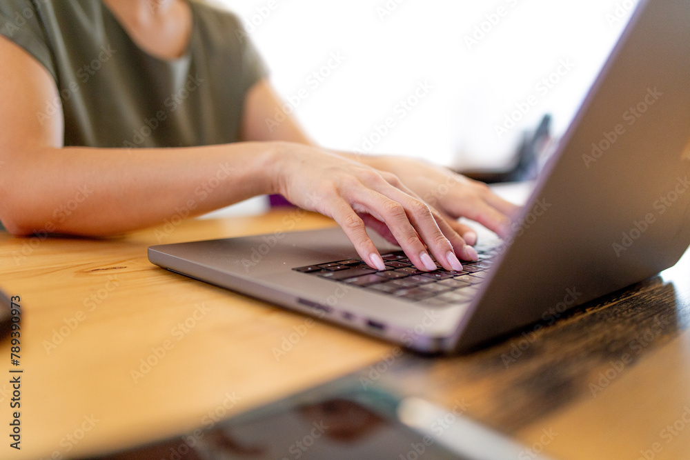 Close-up of woman's hands with her fingers on the keyboard of a laptop in an office Close-up of woman's hands with her fingers on the keyboard of a laptop in an office