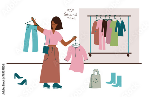  A young woman buys clothes at a flea market or a second-hand store. A girl is shopping at a sale.The concept of sustainable fashion.A cheap garage sale, a second-hand store. 