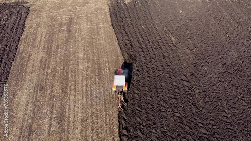 Tractor seeding-sowing crops at agricultural field. Soil loosening aerial slow motion photo