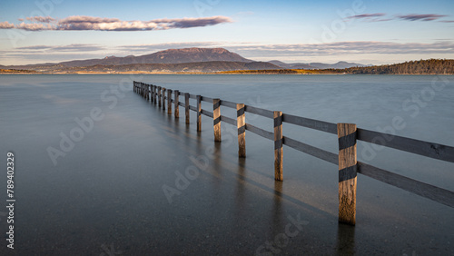 Fence at high tide at Mortimer Bay and Mount Wellington in the background, Tasmania photo