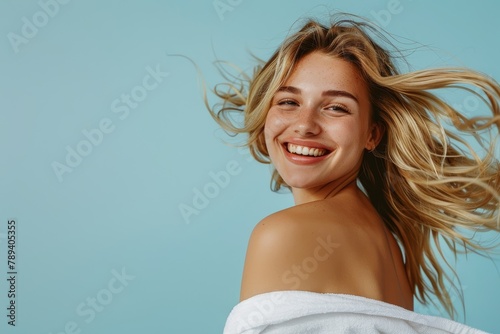 Woman, excited face or expression and blonde hair in motion on gray studio background in frizz free wavy hairstyle. Portrait, pleasant grin, amazing beauty model, and healthy hair or grooming photo