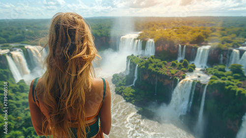 The girl examines the Iguas waterfall from a height. Traveling in Brazil. Girl with her back on a sunny day. photo