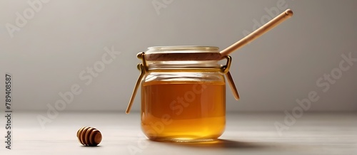 Glass jar of honey with wooden drizzler on colored background Honey pot and dipper high above Top view copy space photo