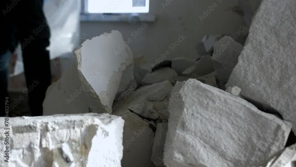 A man puts pieces of destroyed blocks in a bag after dismantling the wall. A man puts pieces of destroyed blocks in a bag after dismantling the wall.