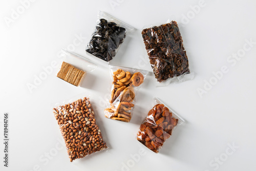 food storage, healthy eating and diet concept - close up of bags with dried fruits, nuts and cookies on white background