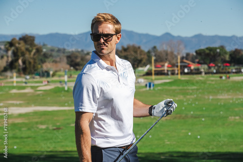 Handsome golfer on the driving range. The man is wearing sunglasses outside. photo