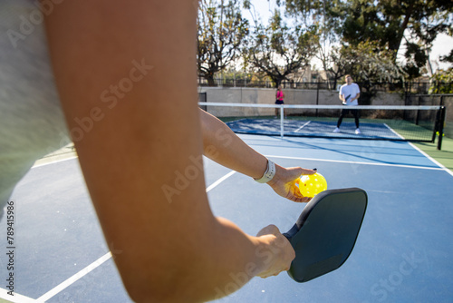 Close up view from perspective of pickleball player ready to serve the ball during a fun game outside. 