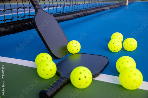 Pickleball paddles and balls on a game court. The sports equipment is ready for game play. 