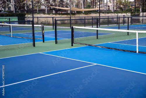 Empty pickleball court outside. The ground is blue and the net is mounted. 